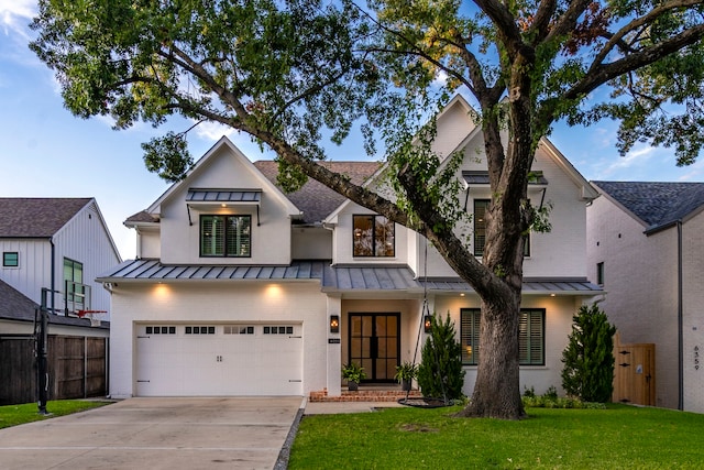 modern inspired farmhouse with brick siding, concrete driveway, a standing seam roof, fence, and a front lawn