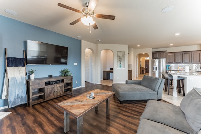 living room with arched walkways, ceiling fan, recessed lighting, wood finished floors, and baseboards