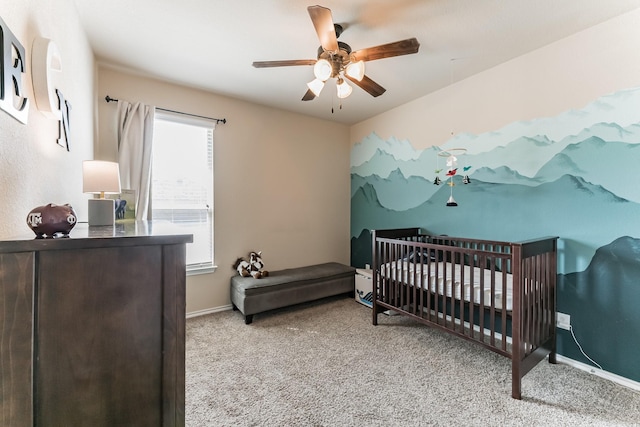 carpeted bedroom featuring a nursery area, baseboards, and a ceiling fan