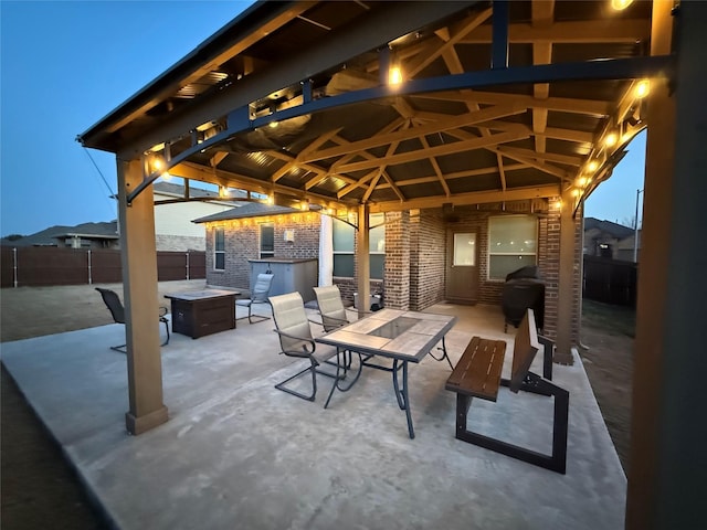 view of patio featuring an outdoor fire pit, fence, outdoor dining area, and a gazebo