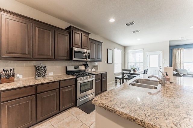 kitchen with stainless steel appliances, a sink, visible vents, and decorative backsplash