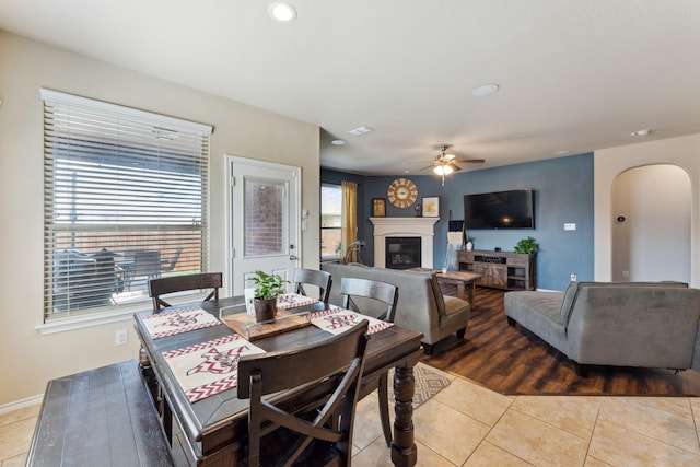 dining space featuring arched walkways, tile patterned flooring, recessed lighting, a ceiling fan, and a glass covered fireplace