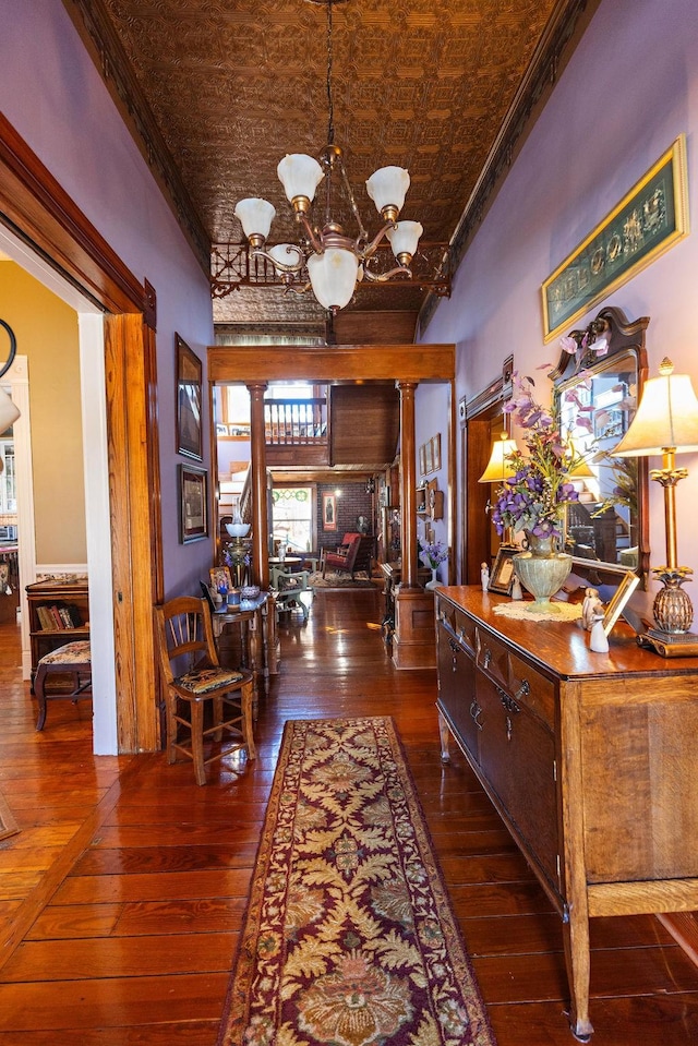 corridor with ornate columns, a notable chandelier, wood-type flooring, and an ornate ceiling