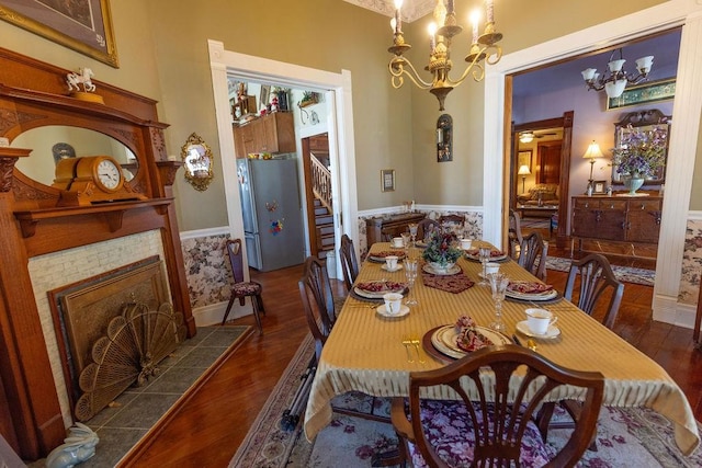 dining room with a notable chandelier, a fireplace, stairs, and wood finished floors