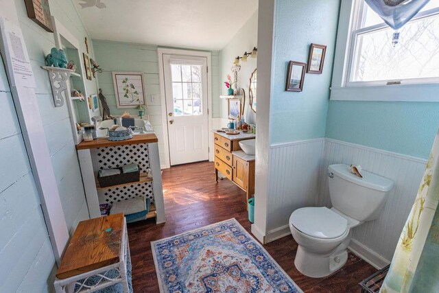 bathroom with a wainscoted wall, toilet, vanity, and wood finished floors