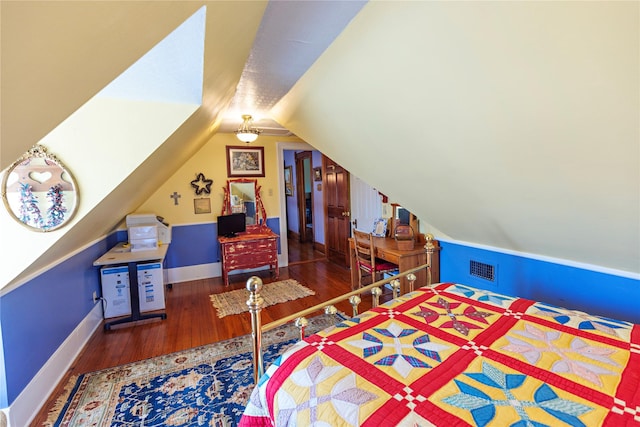 bedroom with lofted ceiling, wood finished floors, visible vents, and baseboards