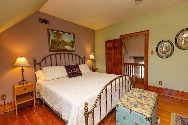 bedroom featuring visible vents, baseboards, lofted ceiling, and wood finished floors