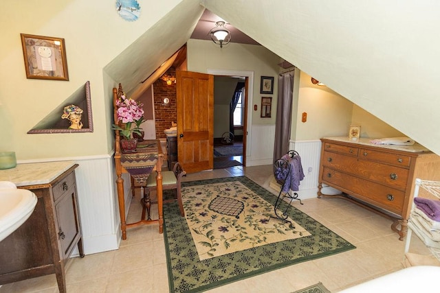 interior space featuring lofted ceiling, light tile patterned flooring, and wainscoting