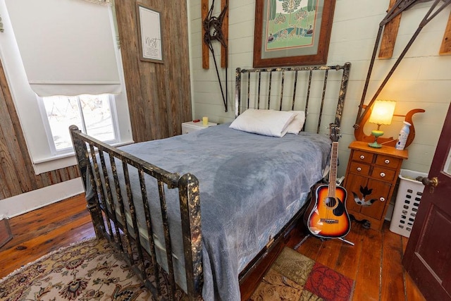 bedroom with hardwood / wood-style floors and wooden walls