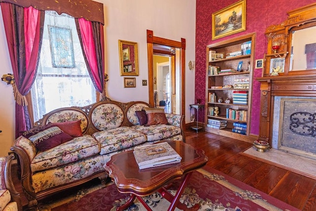 living room with a premium fireplace, built in features, a healthy amount of sunlight, and wood-type flooring