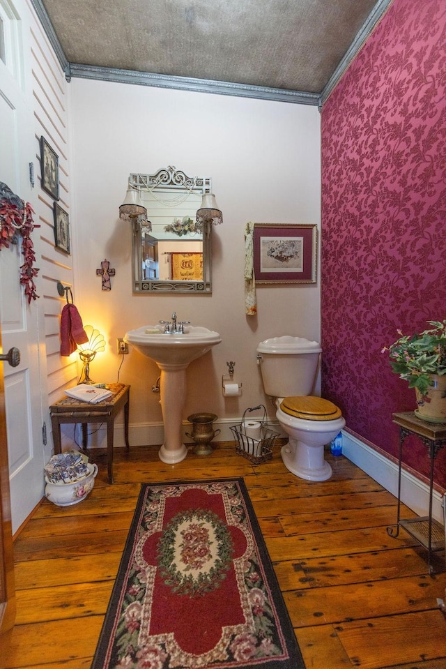 half bath featuring toilet, baseboards, and wood finished floors