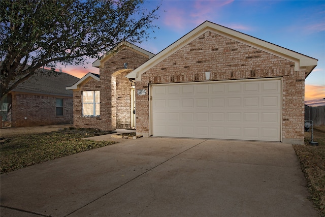 ranch-style home with an attached garage, brick siding, and driveway