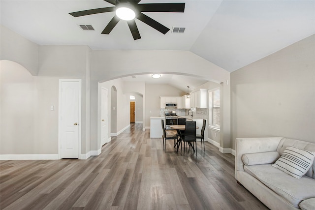 living room featuring vaulted ceiling, wood finished floors, visible vents, and baseboards