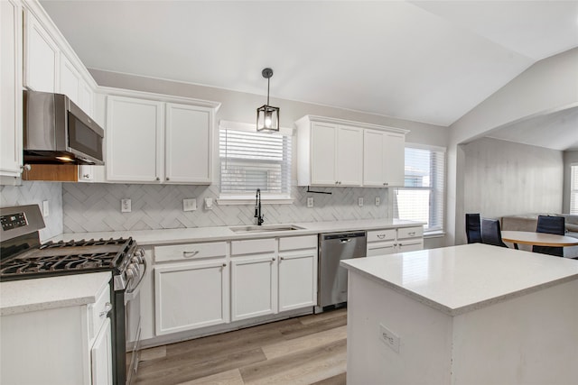 kitchen with lofted ceiling, light wood-style flooring, a sink, white cabinets, and appliances with stainless steel finishes