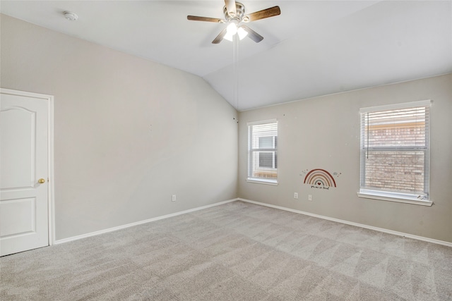 empty room featuring lofted ceiling, carpet flooring, baseboards, and ceiling fan