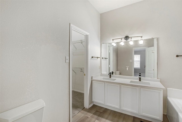 bathroom with double vanity, toilet, wood finished floors, and a sink