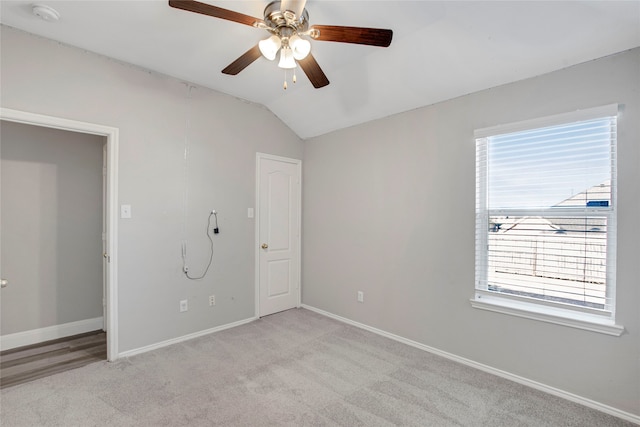 interior space with lofted ceiling, light colored carpet, baseboards, and ceiling fan