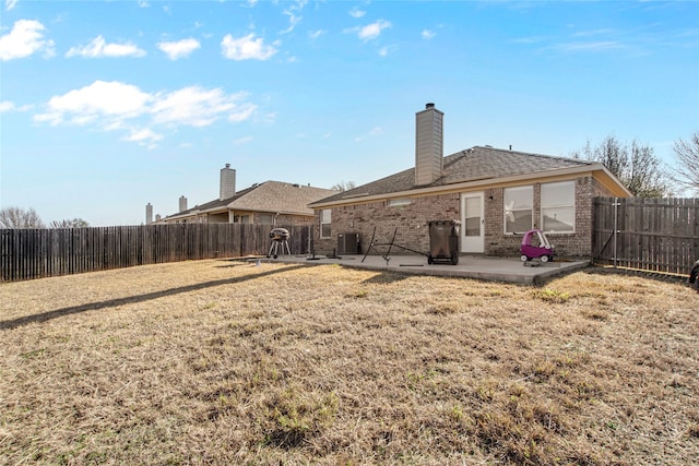 back of property with a yard, a fenced backyard, brick siding, and a patio