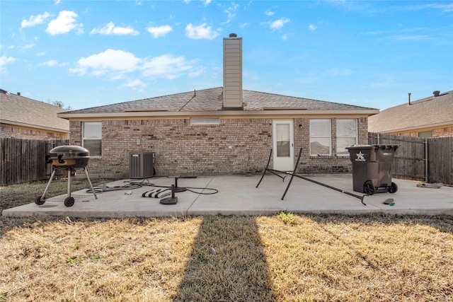 rear view of property featuring a patio area, a chimney, brick siding, and a fenced backyard