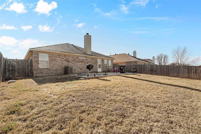 back of property with a yard, a fenced backyard, brick siding, and a patio