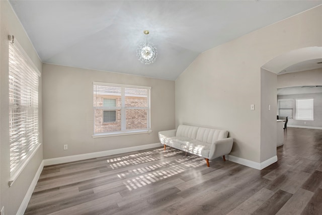 sitting room featuring lofted ceiling, plenty of natural light, wood finished floors, and arched walkways