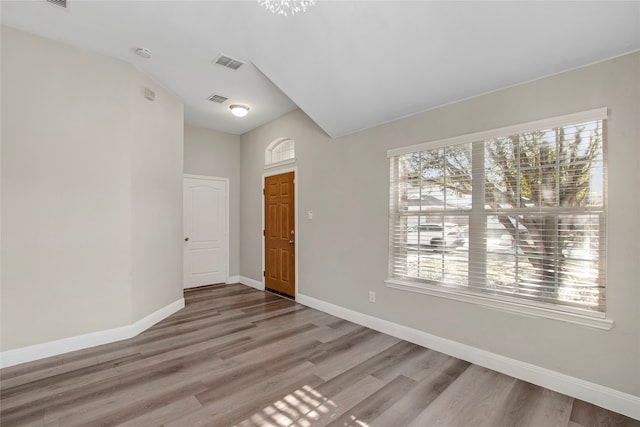 foyer with light wood-style floors, baseboards, and visible vents