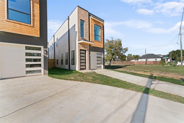 view of side of home featuring driveway, a lawn, and an attached garage