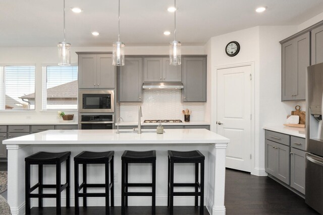 1624 Thunderbird Dr, Fort Worth, TX 76052 - kitchen featuring tasteful backsplash, gray cabinets, stainless steel appliances, a kitchen bar, and under cabinet range hood