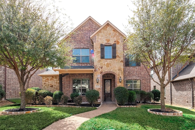 view of front of home featuring stone siding, a front lawn, and brick siding