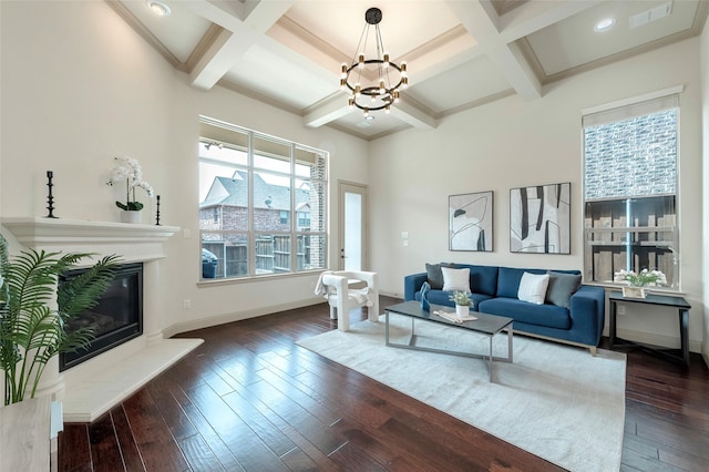 living room featuring baseboards, coffered ceiling, visible vents, dark wood finished floors, and a glass covered fireplace