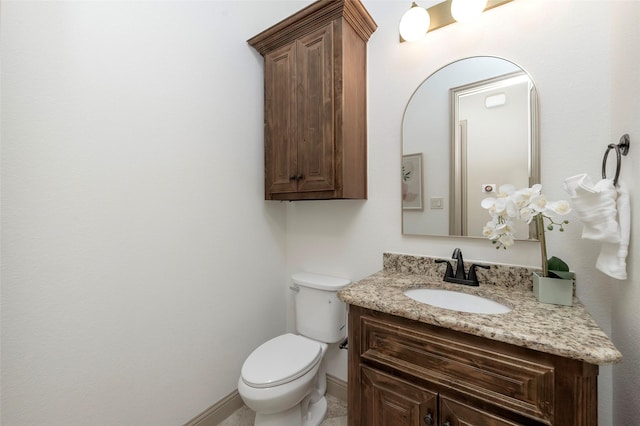 bathroom with toilet, baseboards, and vanity