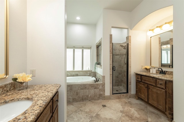 full bath featuring a stall shower, two vanities, a sink, and a bath