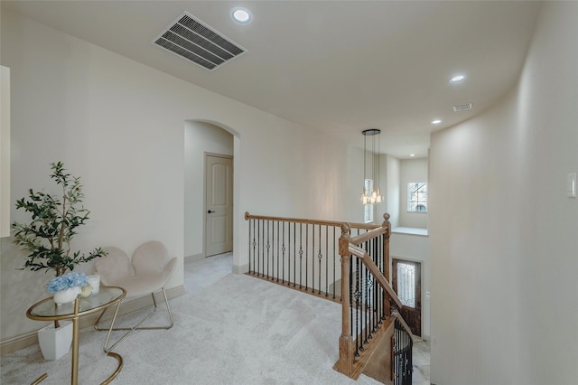 living area with arched walkways, light carpet, an upstairs landing, and visible vents