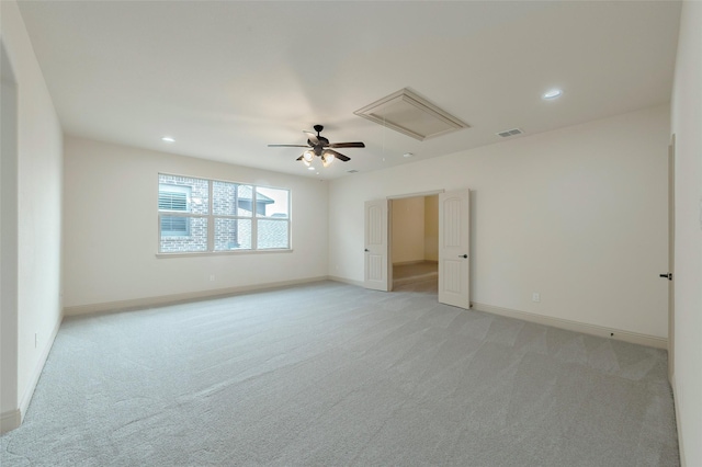 empty room with attic access, visible vents, light carpet, and baseboards