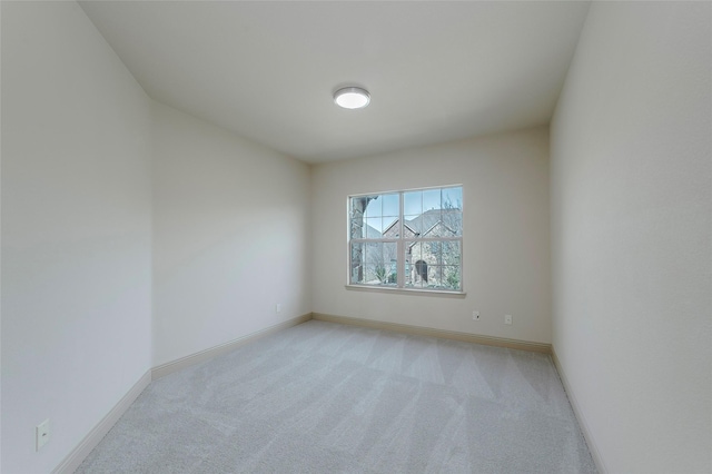 unfurnished room with baseboards and light colored carpet