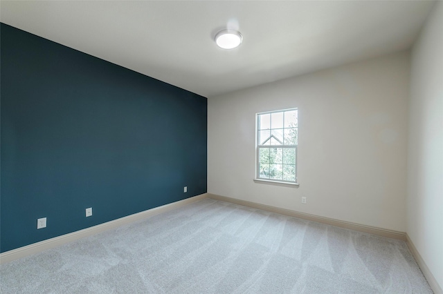 unfurnished room with light carpet and baseboards