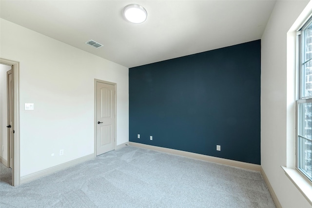 unfurnished room with light carpet, visible vents, and baseboards