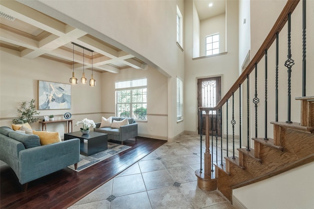 tiled foyer featuring baseboards, coffered ceiling, a towering ceiling, stairway, and beam ceiling