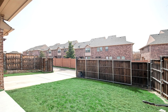 view of yard with a patio area, a fenced backyard, and a residential view