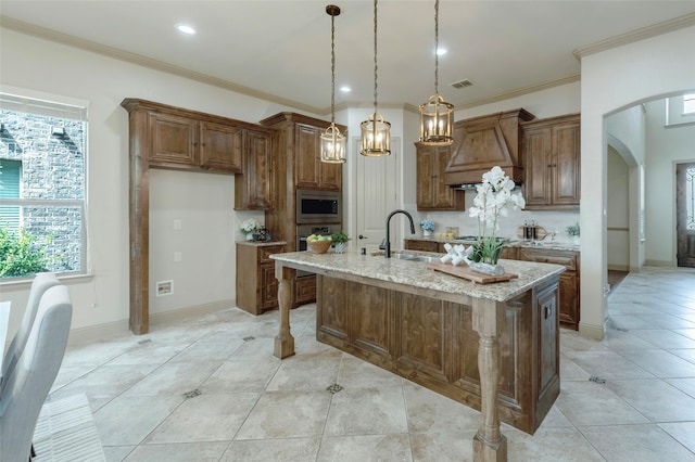 kitchen with arched walkways, light tile patterned flooring, stainless steel appliances, premium range hood, and a sink