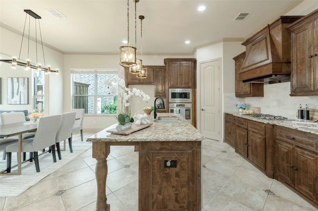 kitchen with tasteful backsplash, visible vents, appliances with stainless steel finishes, a sink, and premium range hood