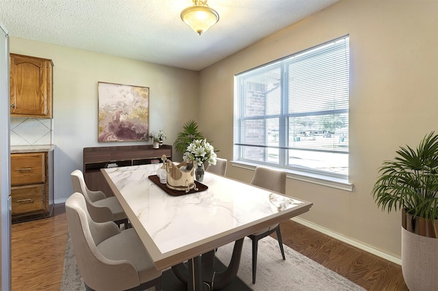 dining room with dark wood-style floors, a textured ceiling, and baseboards