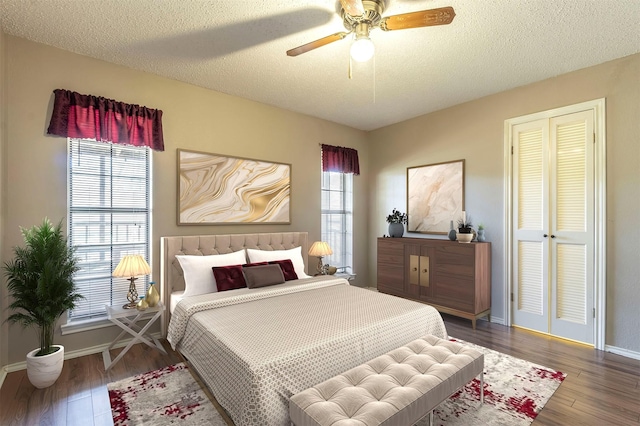 bedroom featuring a textured ceiling, multiple windows, baseboards, and wood finished floors