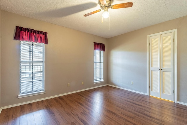 spare room with a textured ceiling, wood finished floors, a ceiling fan, and baseboards