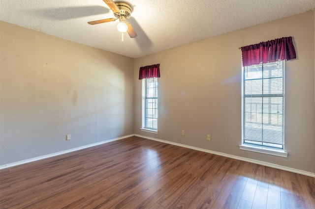 spare room with a textured ceiling, baseboards, and wood finished floors