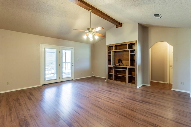 unfurnished living room with visible vents, arched walkways, lofted ceiling with beams, wood finished floors, and a textured ceiling