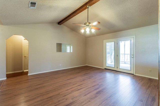 empty room with visible vents, arched walkways, lofted ceiling with beams, dark wood-style floors, and a textured ceiling