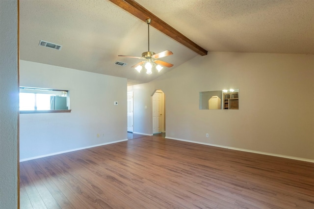 empty room featuring vaulted ceiling with beams, visible vents, arched walkways, and wood finished floors