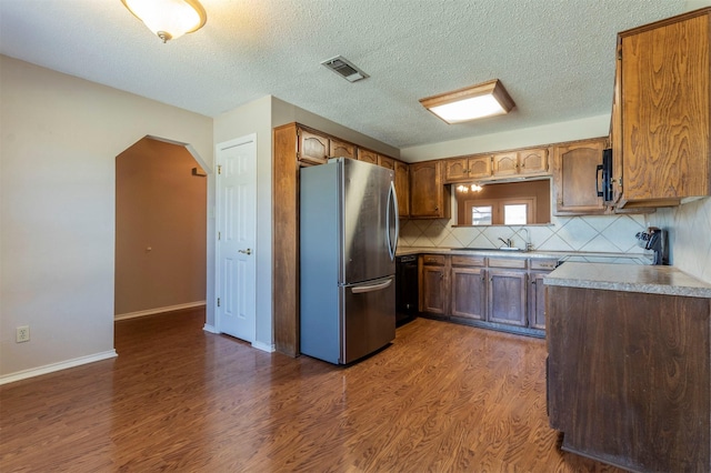 kitchen featuring visible vents, dark wood finished floors, arched walkways, and freestanding refrigerator