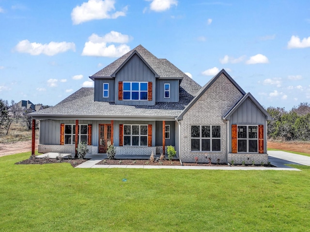 view of front of property featuring a shingled roof, a front lawn, board and batten siding, and brick siding